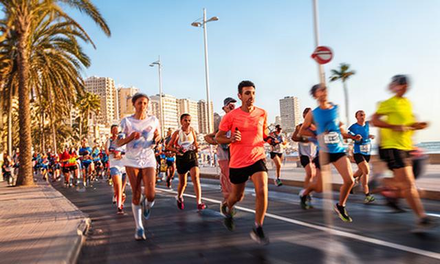 Corredores avanzando por una avenida costera durante una carrera popular de Benidorm